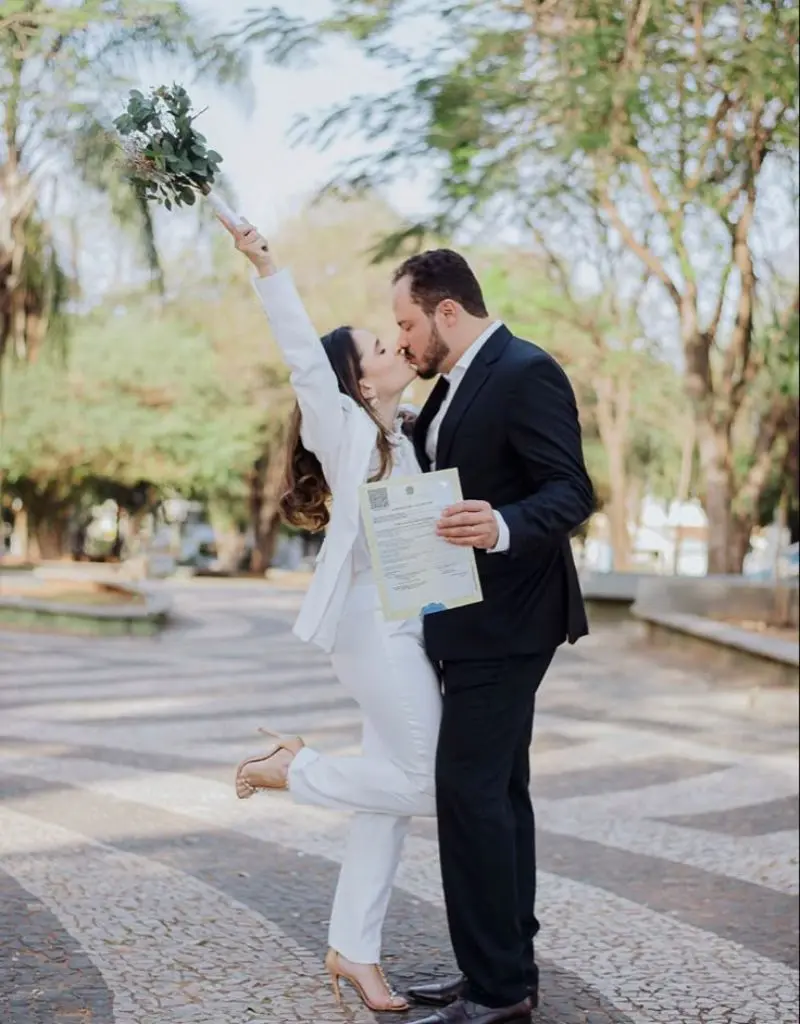 casal se beijando segurando a certid&atilde;o de casamento