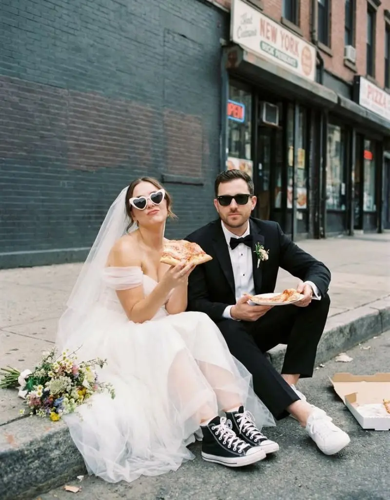 casal sentado comendo pizza na cal&ccedil;ada