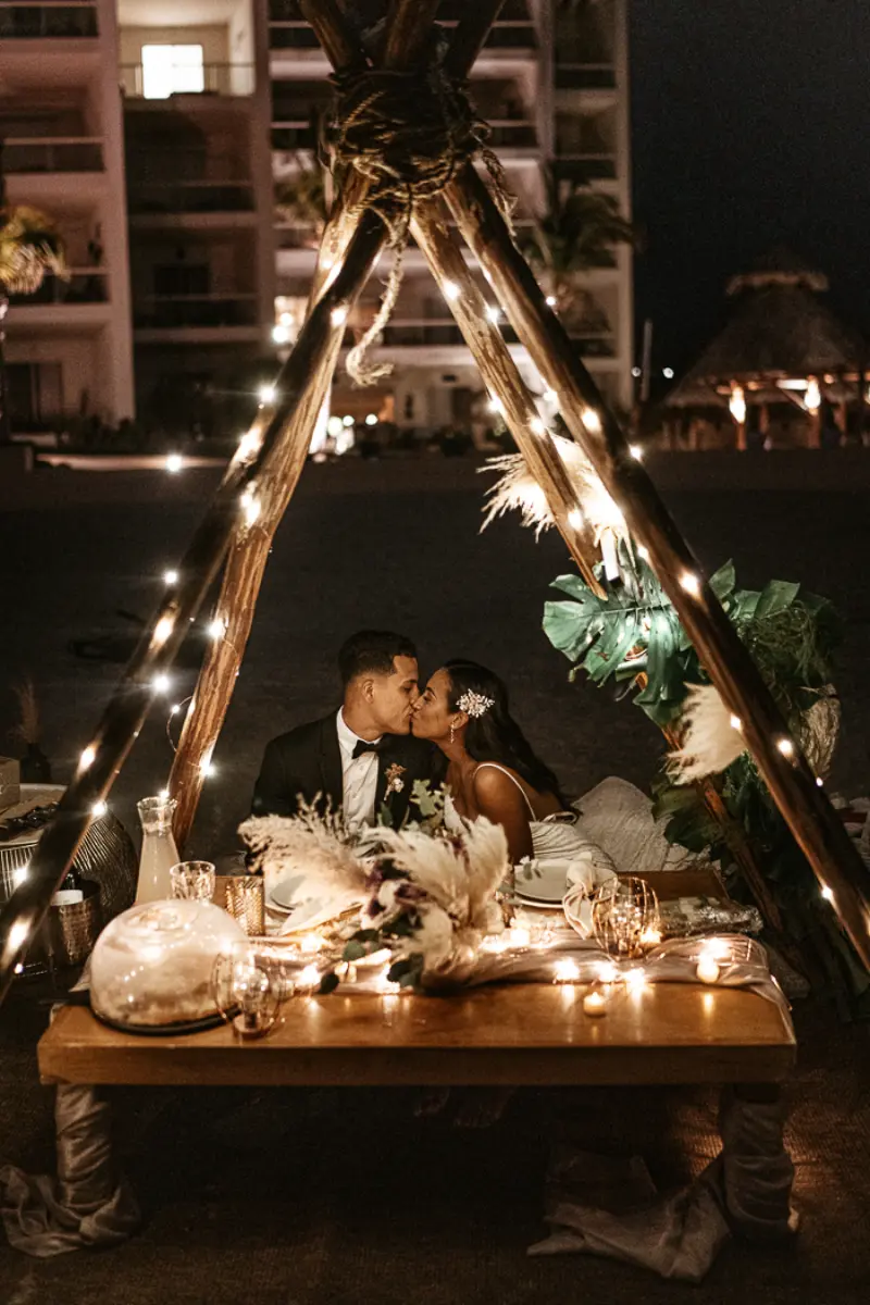 casal sentados em tenda de luzes em casamento intimista na praia