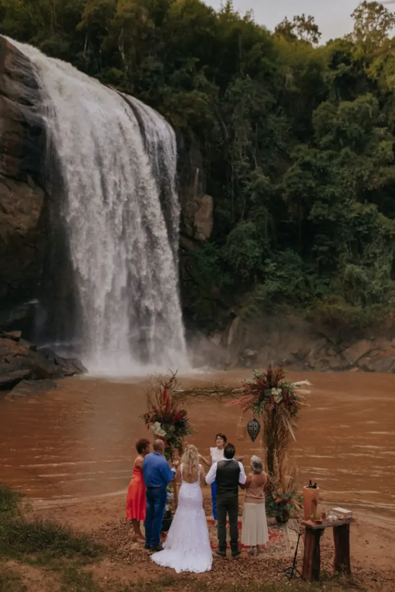 micro wedding na cachoeira com casal e convidados durante a cerim&ocirc;nia