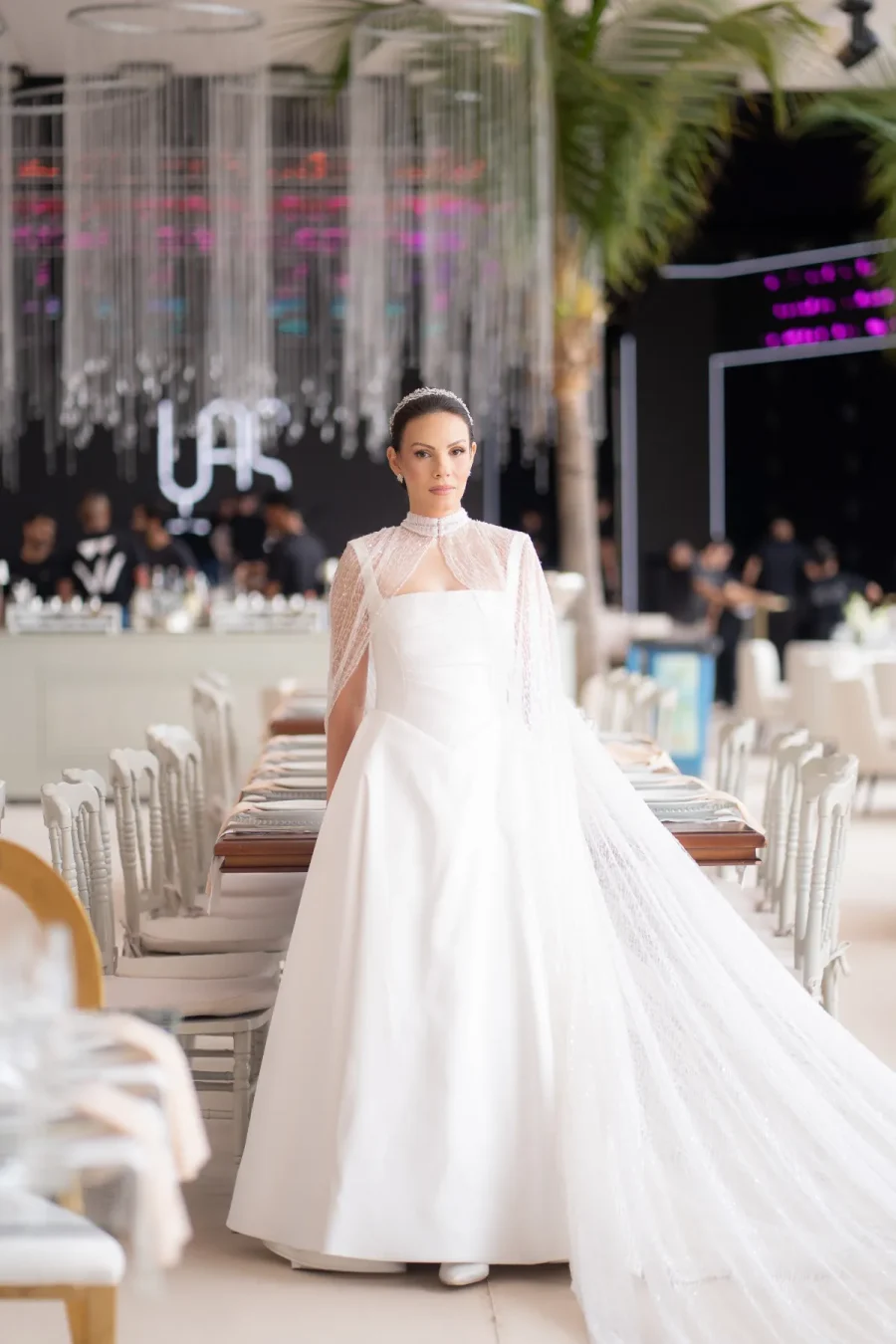 mulher com vestido de noiva com capa na frente da mesa