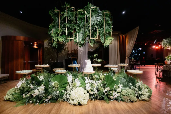 mesa de bolo de casamento com plantas e flores brancas