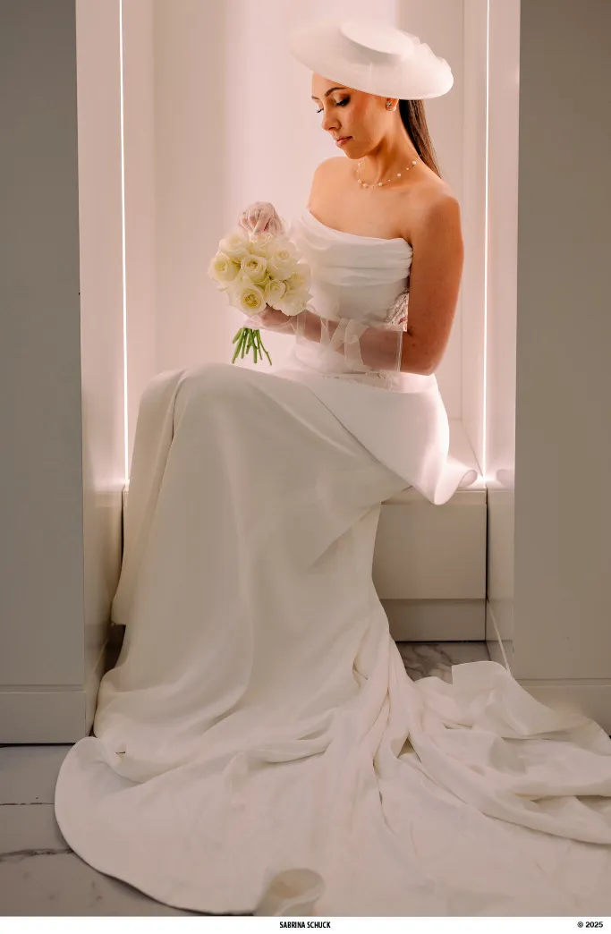 mulher com vestido de noiva com corset e chapéu segurando buquê