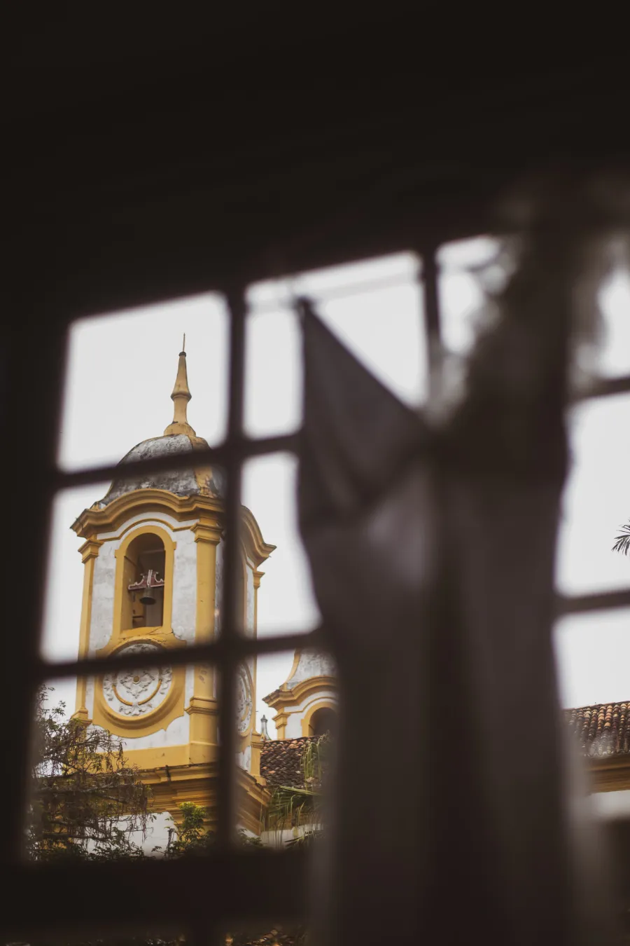 vestido de noiva na janela com vista para a igreja