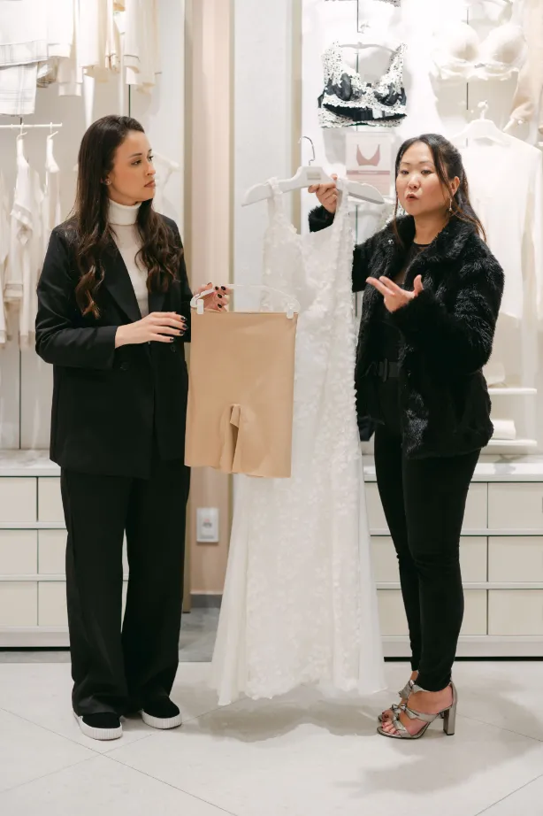 mulheres falando ao lado de vestido de noiva