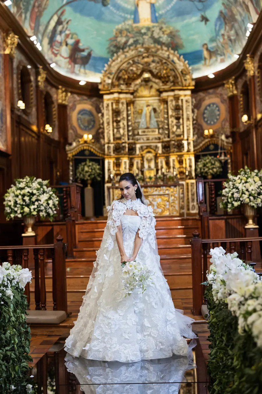 mulher com vestido de noiva com capa bordada na igreja