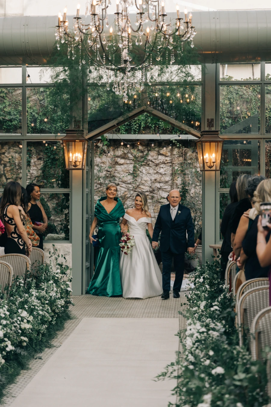 noiva ao lado da mãe de vestido verde e pai de terno azul